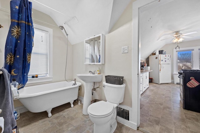 full bath featuring visible vents, a freestanding bath, vaulted ceiling, and toilet