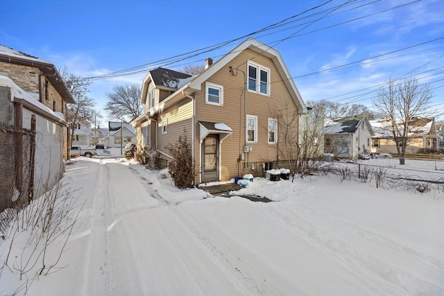 snow covered house with a residential view and fence