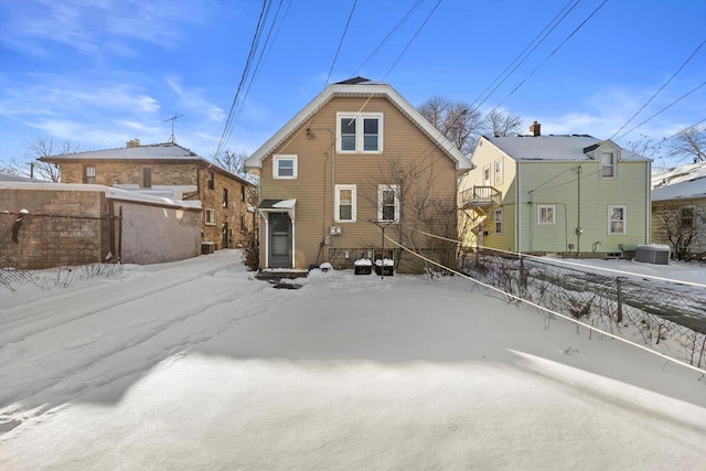 snow covered house with cooling unit and fence