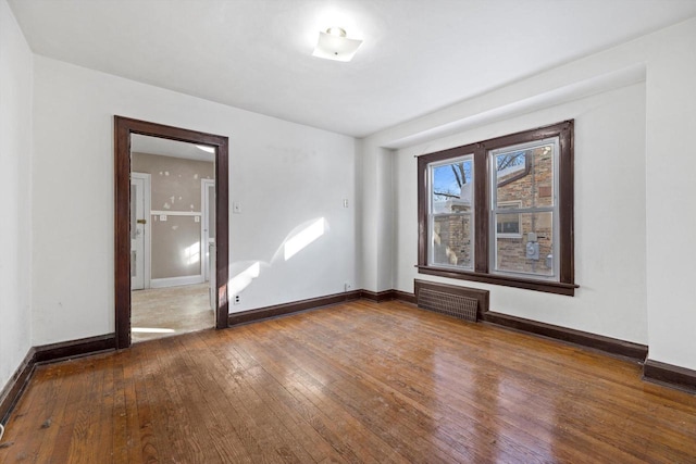 empty room with hardwood / wood-style flooring, baseboards, and visible vents