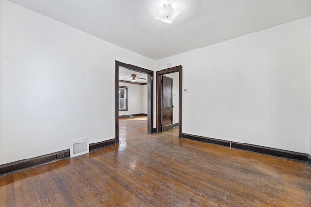 empty room featuring baseboards, visible vents, and wood-type flooring