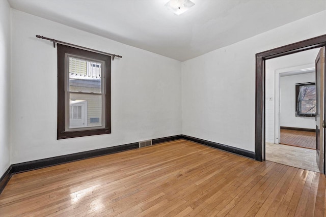 empty room with visible vents, baseboards, and hardwood / wood-style floors