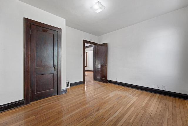 empty room featuring visible vents, baseboards, and light wood finished floors