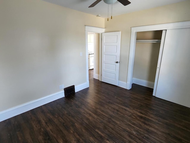 unfurnished bedroom with dark wood-style floors, baseboards, a closet, and ceiling fan