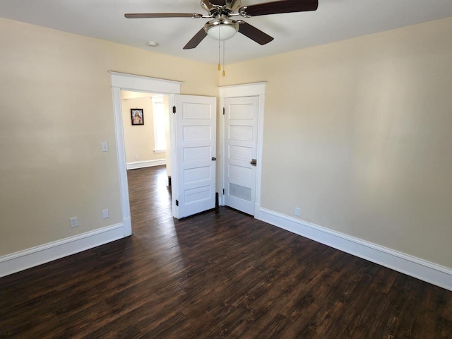 unfurnished room with baseboards, ceiling fan, and dark wood-style flooring