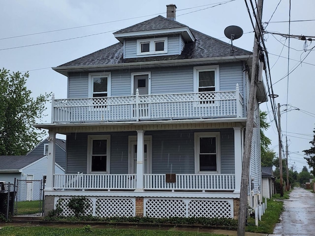 traditional style home with a balcony, covered porch, and a shingled roof