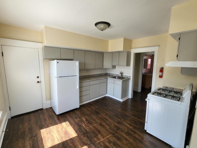 kitchen featuring gray cabinets, a sink, dark wood-style floors, white appliances, and decorative backsplash