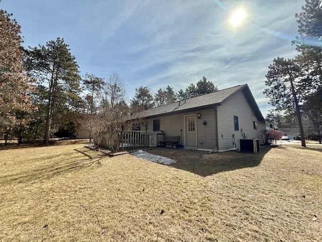 back of property with central air condition unit and a yard