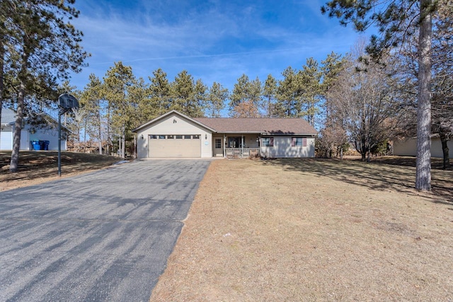 ranch-style home featuring aphalt driveway, an attached garage, covered porch, and a front yard