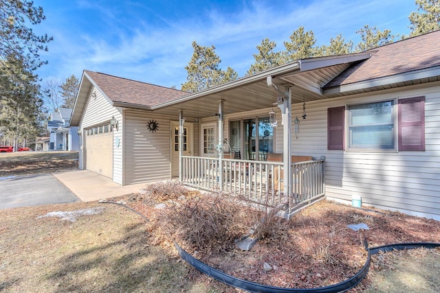 view of front of house featuring driveway, roof with shingles, a porch, and an attached garage