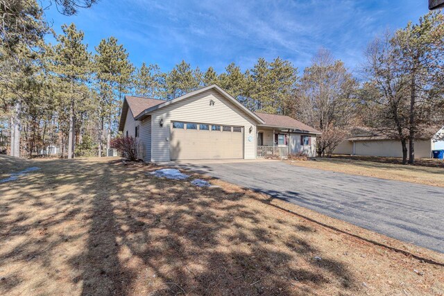 single story home with aphalt driveway, a front yard, and an attached garage