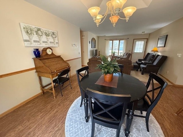 dining space with baseboards, a chandelier, and light wood finished floors