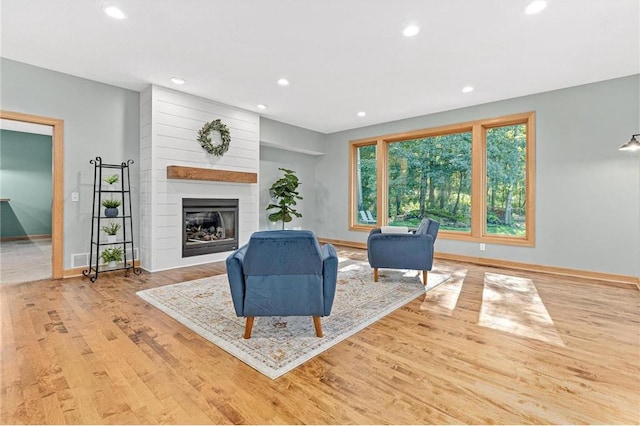 living room featuring recessed lighting, a fireplace, baseboards, and wood finished floors