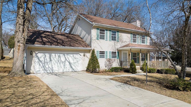 colonial inspired home featuring a porch, an attached garage, concrete driveway, and a chimney