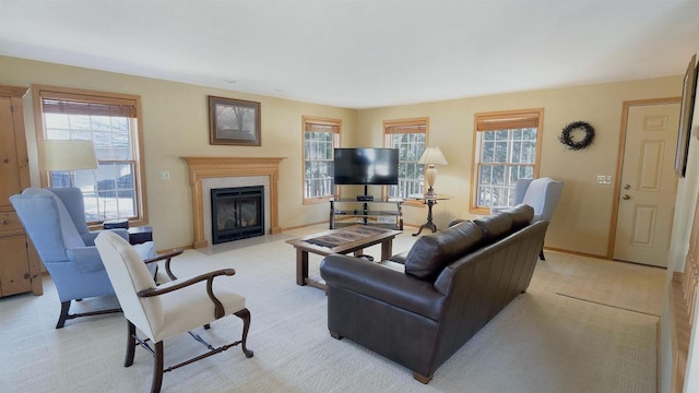 living area with a fireplace with flush hearth, a healthy amount of sunlight, light colored carpet, and baseboards