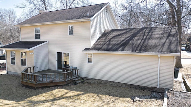 back of property with a wooden deck, roof with shingles, and a chimney