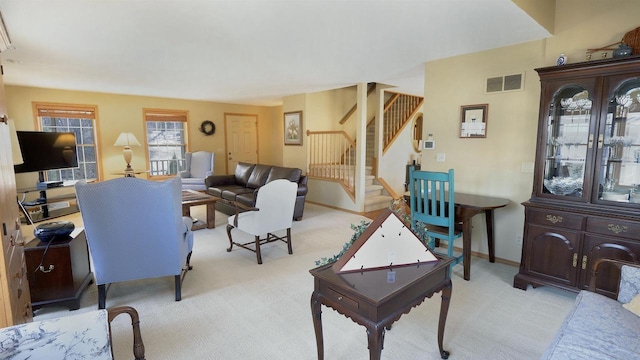 living room with visible vents, light colored carpet, stairway, and baseboards