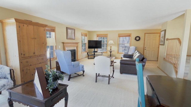 living area featuring light carpet and a glass covered fireplace