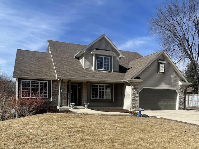 view of front facade with fence, roof with shingles, concrete driveway, a front lawn, and stone siding