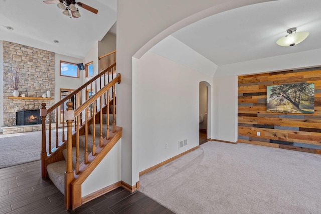 staircase featuring arched walkways, visible vents, a fireplace, and baseboards