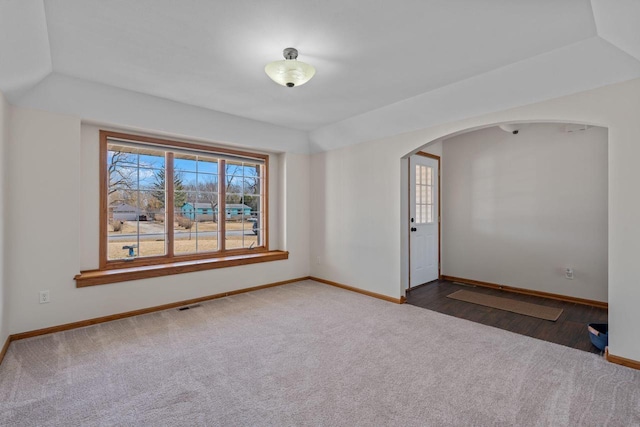 unfurnished room featuring carpet flooring, arched walkways, visible vents, and baseboards