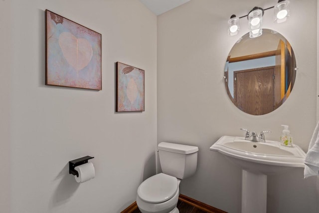 half bath featuring baseboards and toilet