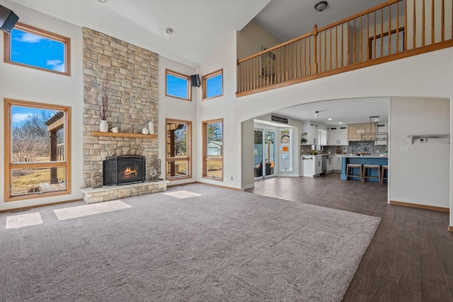 unfurnished living room featuring baseboards, arched walkways, dark wood-style floors, and a fireplace