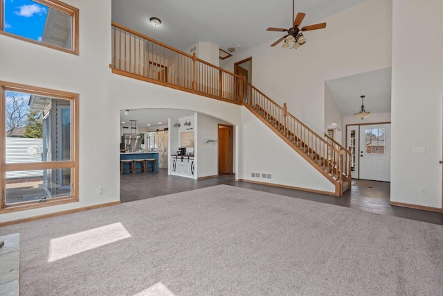 unfurnished living room featuring visible vents, baseboards, stairway, carpet floors, and arched walkways