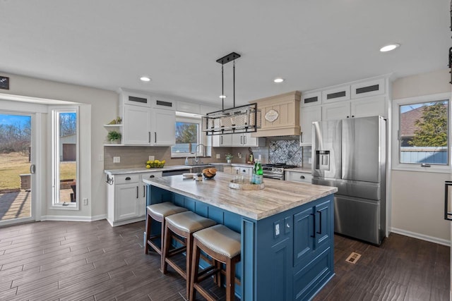 kitchen featuring tasteful backsplash, a center island, a breakfast bar, stainless steel appliances, and a sink