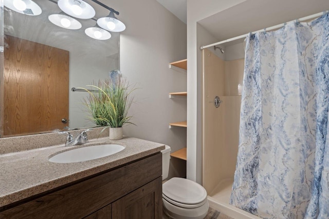 bathroom featuring toilet, a stall shower, and vanity