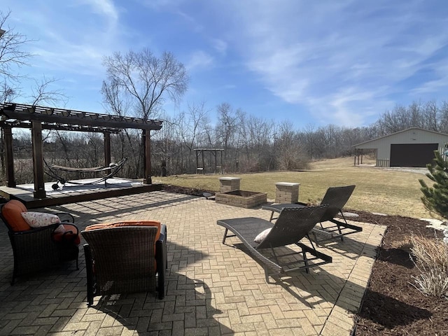 view of patio / terrace featuring an outbuilding, a fire pit, a pergola, and a detached garage