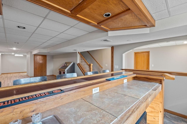 bar featuring visible vents, stairs, a paneled ceiling, and baseboards