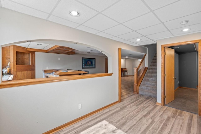 interior space featuring stairs, wood finished floors, baseboards, and a paneled ceiling