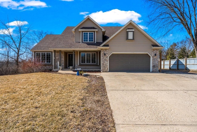 view of front of home featuring a front lawn, fence, a garage, stone siding, and driveway