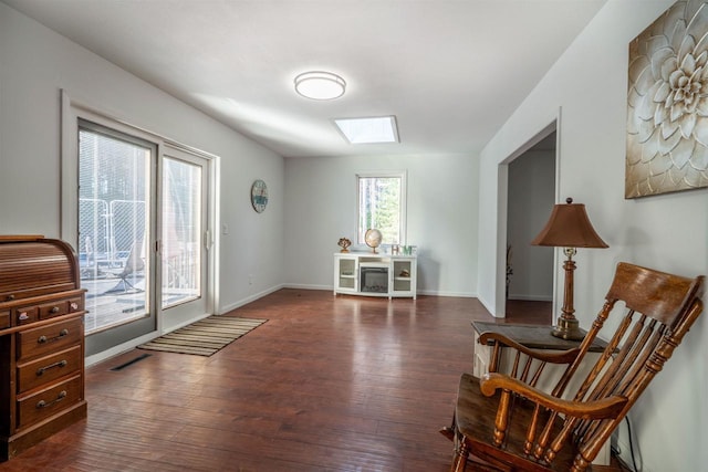 sitting room with a skylight, baseboards, and dark wood-style flooring