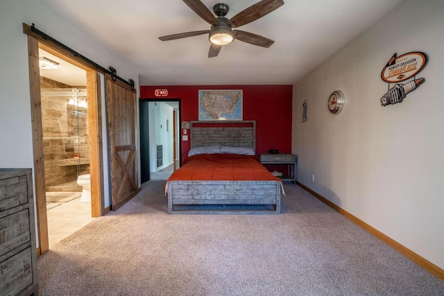 unfurnished bedroom featuring ceiling fan, baseboards, carpet, a barn door, and ensuite bathroom