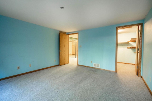 unfurnished bedroom featuring visible vents, baseboards, carpet flooring, and a spacious closet