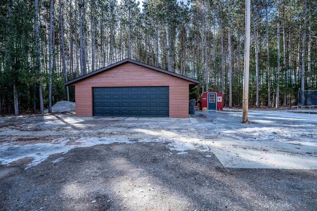 detached garage with a trampoline and a view of trees