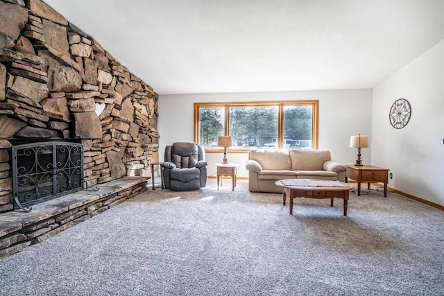 living area featuring baseboards, carpet, a stone fireplace, and vaulted ceiling