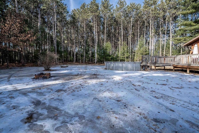 view of yard featuring a forest view and a wooden deck