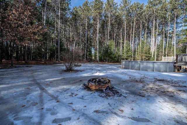 exterior space with a wooded view, an outdoor pool, and an outdoor fire pit