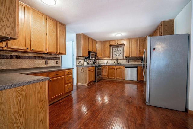 kitchen with dark countertops, tasteful backsplash, dark wood-style flooring, and appliances with stainless steel finishes