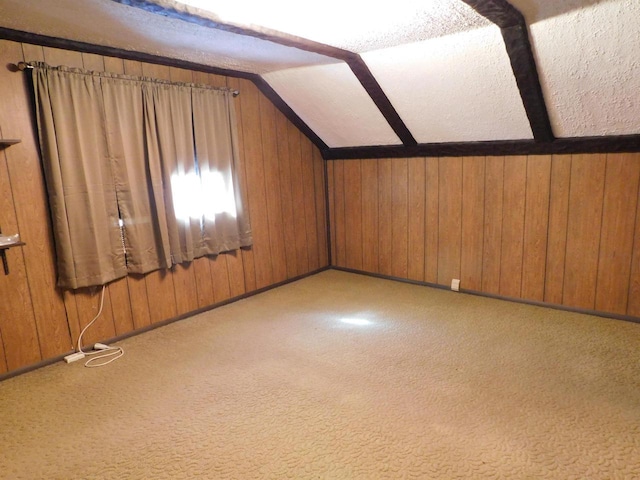 bonus room with carpet floors, wood walls, and vaulted ceiling