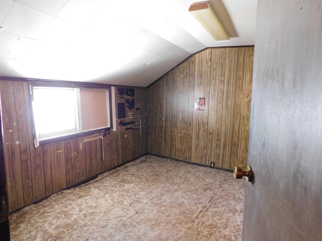 additional living space with vaulted ceiling, wooden walls, and carpet flooring