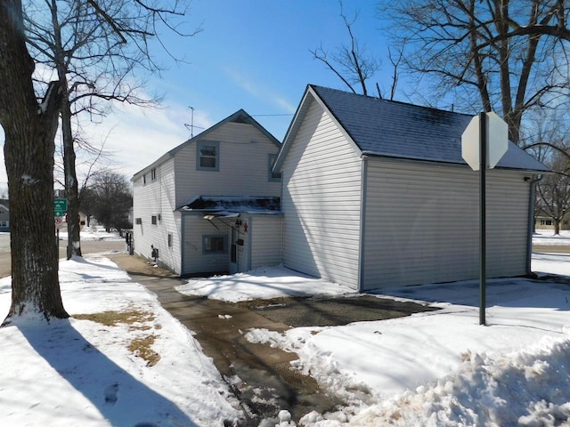 view of snow covered exterior with roof with shingles