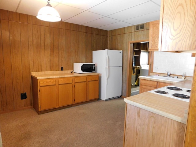 kitchen featuring a sink, white appliances, wood walls, and light countertops