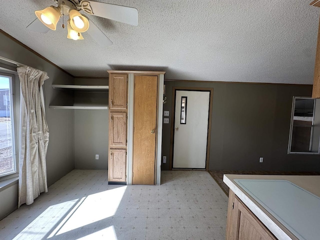 kitchen with a ceiling fan, light floors, brown cabinetry, and a textured ceiling