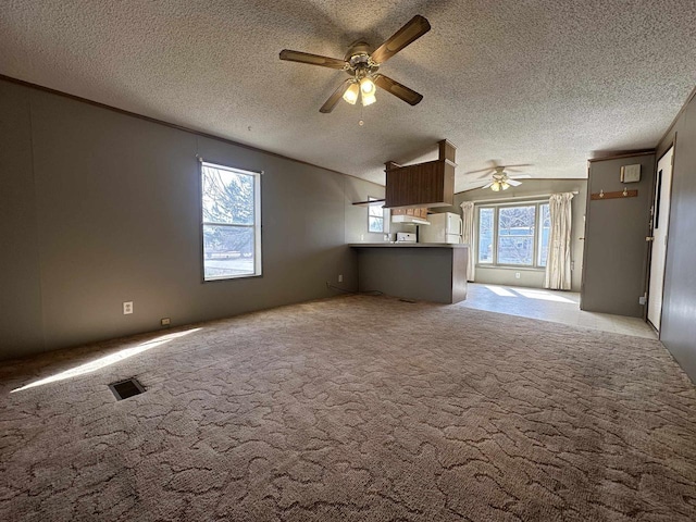 unfurnished living room featuring visible vents, ceiling fan, lofted ceiling, light carpet, and a textured ceiling