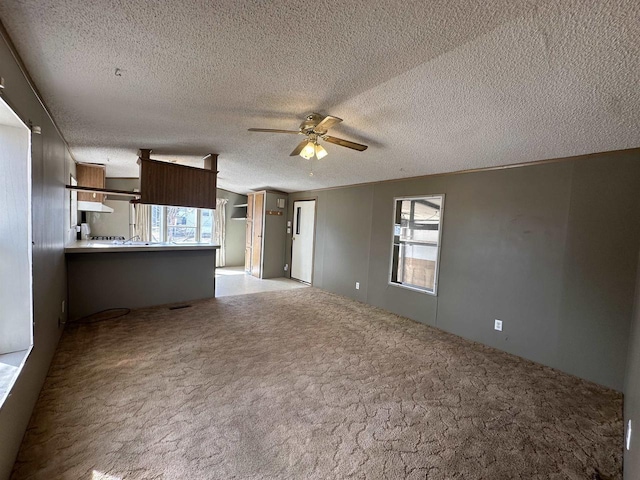 unfurnished living room featuring visible vents, a ceiling fan, carpet flooring, and a textured ceiling