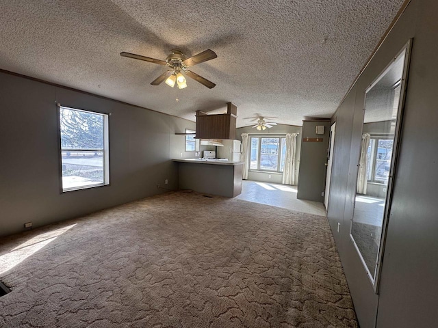 unfurnished living room with a ceiling fan, carpet flooring, and a textured ceiling